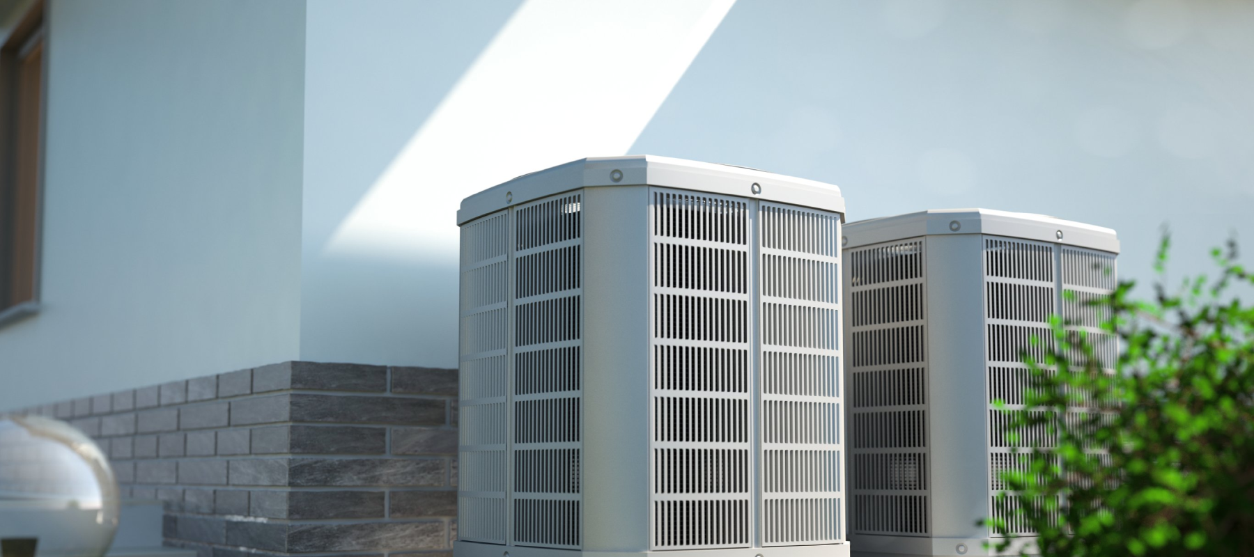 Two outdoor air conditioning units positioned next to a house wall.
